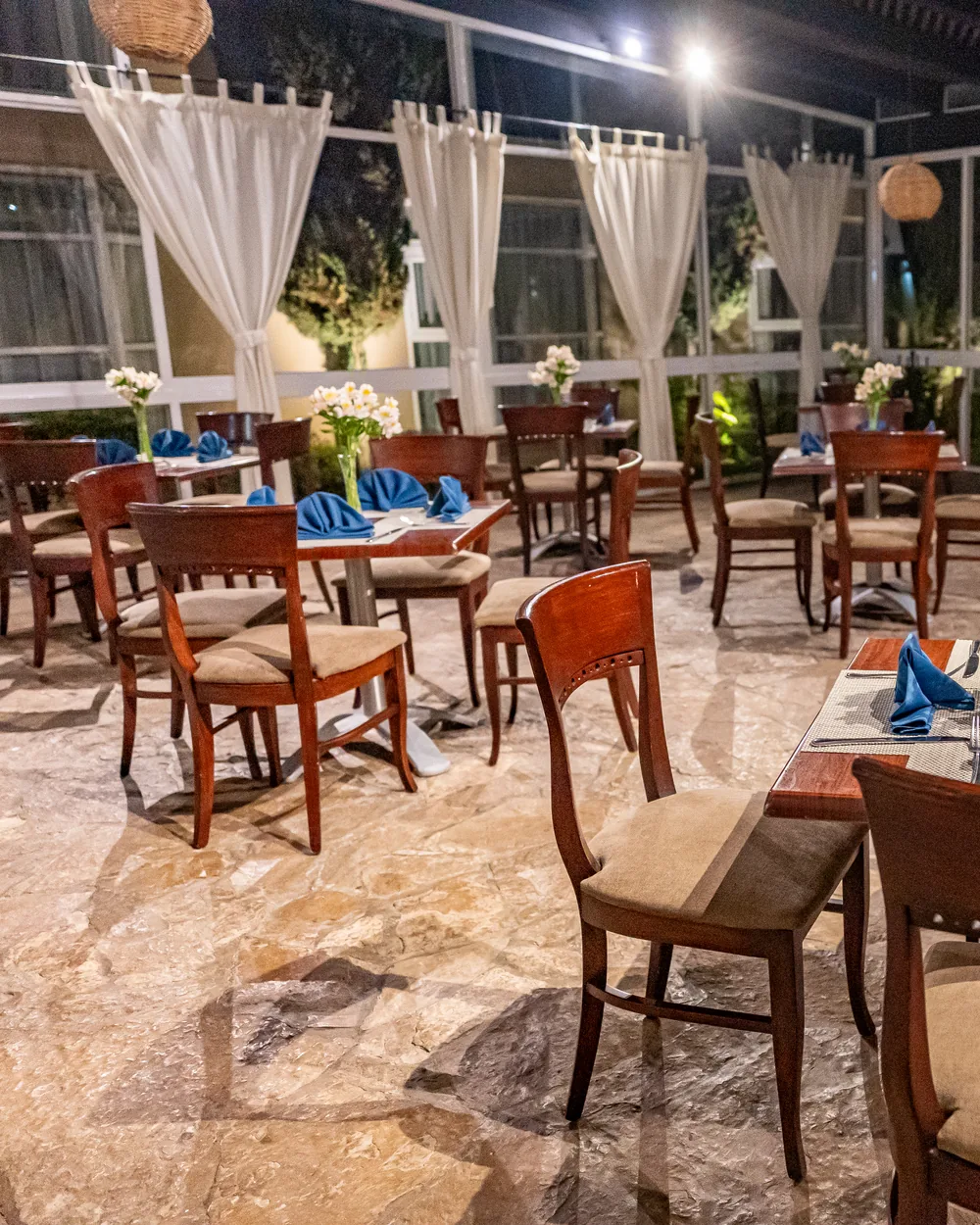 Mesas del comedor por la noche, con las cortinas abiertas al jardín