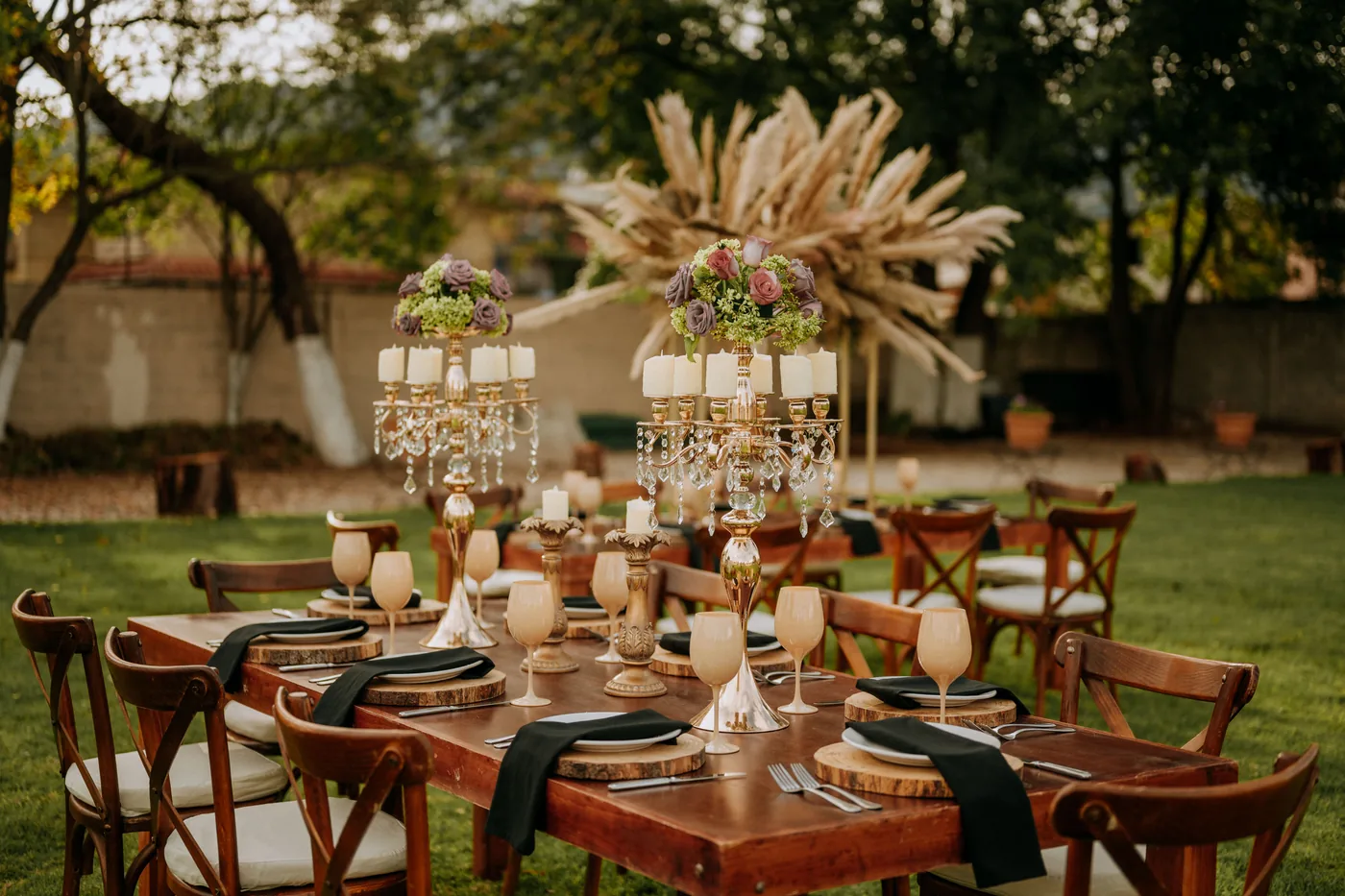 Mesa de celebración montada en el jardín con centros de pampas y velas