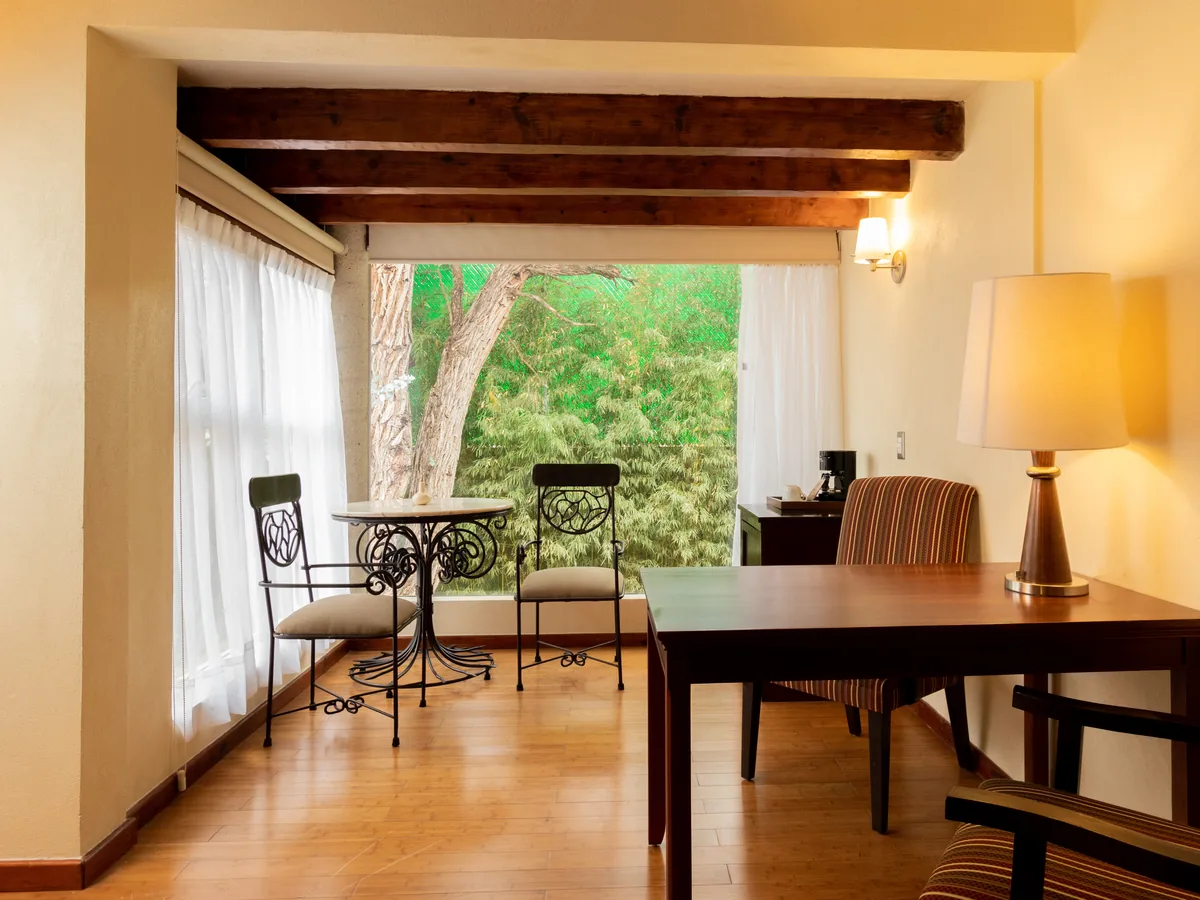 Ver: Mesa junto al ventanal de la Junior Suite, con los árboles del jardín afuera